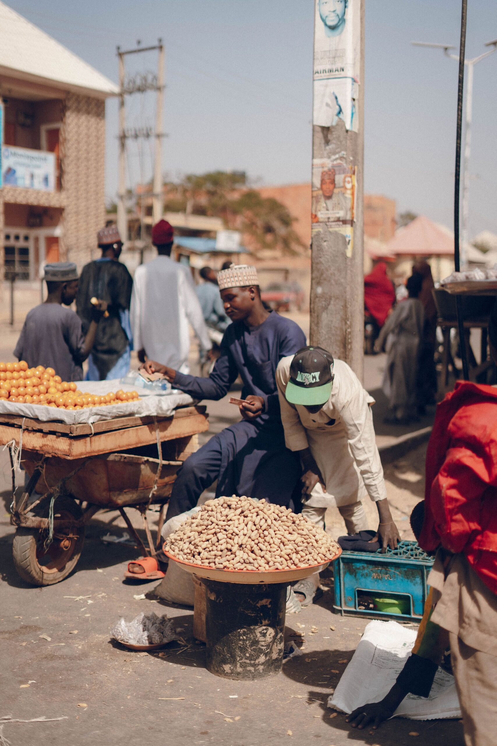 Lively street market in Africa with vendors selling fruits and peanuts.